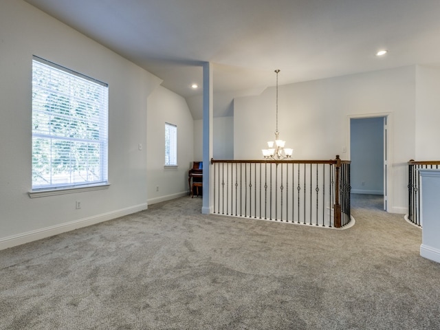 unfurnished room featuring an inviting chandelier, vaulted ceiling, and light carpet