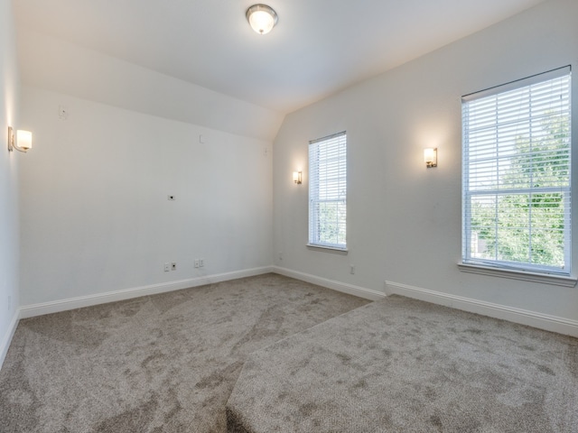 spare room featuring lofted ceiling and light carpet