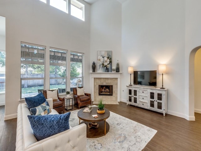 living room featuring a high ceiling, a fireplace, and dark hardwood / wood-style floors