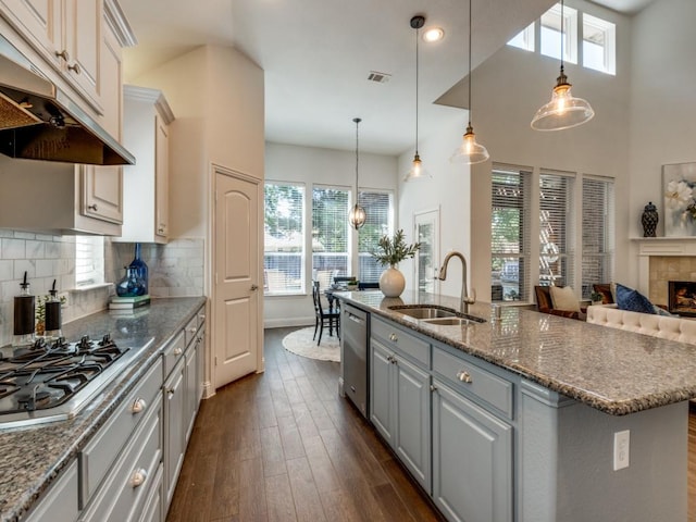 kitchen featuring sink, stainless steel appliances, tasteful backsplash, an island with sink, and pendant lighting