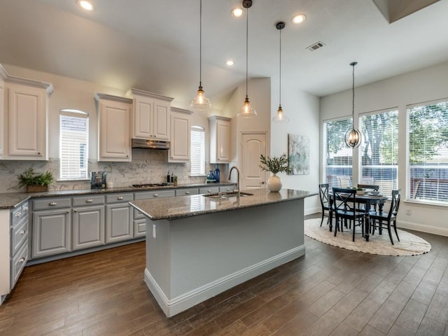 kitchen with white cabinets, a center island with sink, hanging light fixtures, and sink