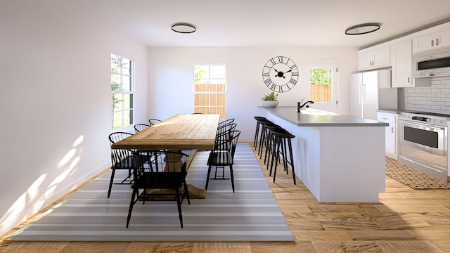 kitchen featuring white appliances, light hardwood / wood-style flooring, a breakfast bar, sink, and white cabinets