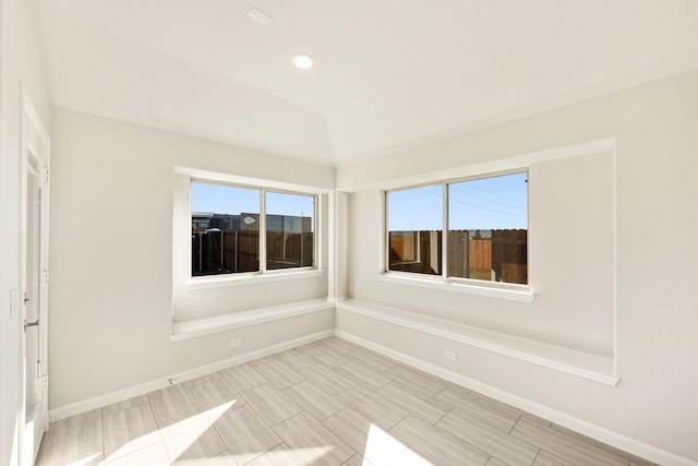 unfurnished room with lofted ceiling and a healthy amount of sunlight