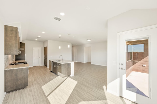 kitchen with sink, decorative light fixtures, stainless steel appliances, and a center island with sink