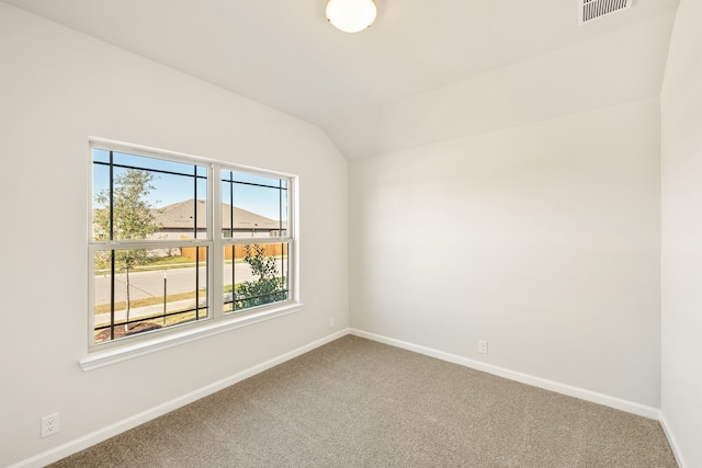 carpeted empty room featuring vaulted ceiling