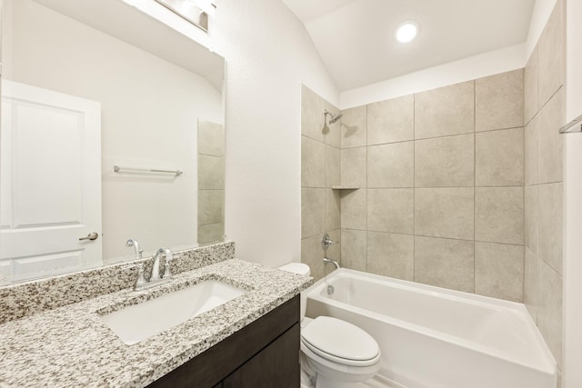 full bathroom featuring tiled shower / bath, lofted ceiling, vanity, and toilet