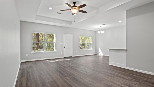 unfurnished room with ceiling fan with notable chandelier, a tray ceiling, and dark hardwood / wood-style floors