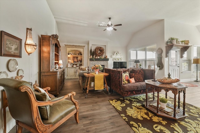 living area featuring dark hardwood / wood-style flooring, a brick fireplace, vaulted ceiling, and ceiling fan