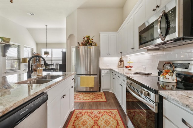 kitchen featuring sink, white cabinetry, light stone counters, decorative light fixtures, and appliances with stainless steel finishes