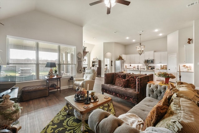 living room with dark hardwood / wood-style flooring, ceiling fan with notable chandelier, and high vaulted ceiling