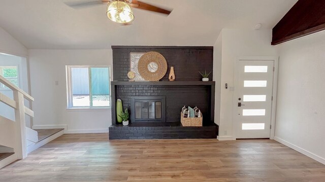 unfurnished living room featuring a fireplace, lofted ceiling, ceiling fan, and light hardwood / wood-style floors