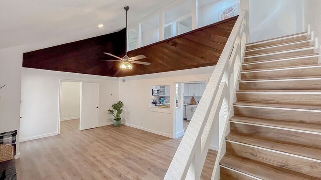 stairway featuring high vaulted ceiling, hardwood / wood-style floors, and ceiling fan