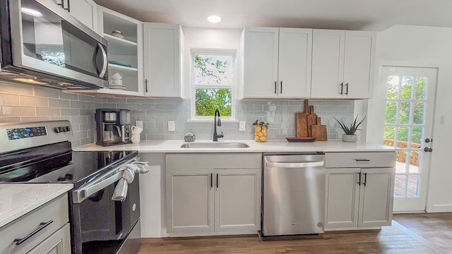 kitchen featuring hardwood / wood-style floors, stainless steel appliances, sink, decorative backsplash, and white cabinets