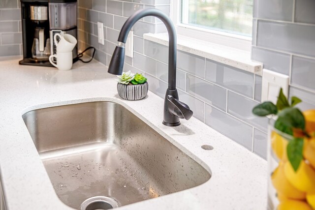 details with backsplash, sink, and light stone countertops