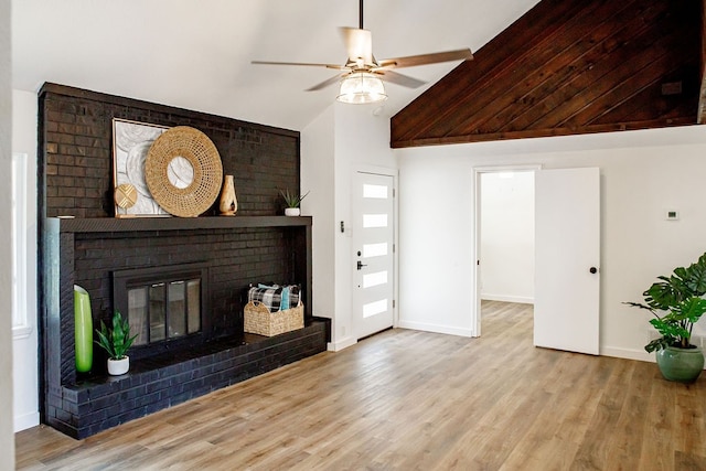 unfurnished living room featuring ceiling fan, light wood-type flooring, a brick fireplace, and vaulted ceiling