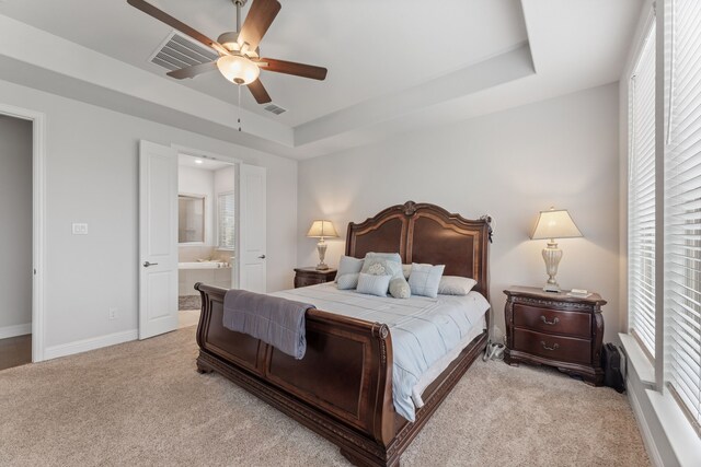 carpeted bedroom with a raised ceiling, ceiling fan, and ensuite bathroom