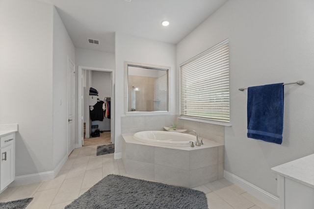 bathroom with tile patterned flooring, vanity, and tiled tub