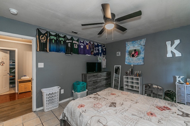 bedroom featuring ceiling fan, light hardwood / wood-style floors, and a textured ceiling