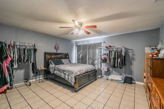 bedroom featuring ceiling fan, light tile patterned floors, and a textured ceiling