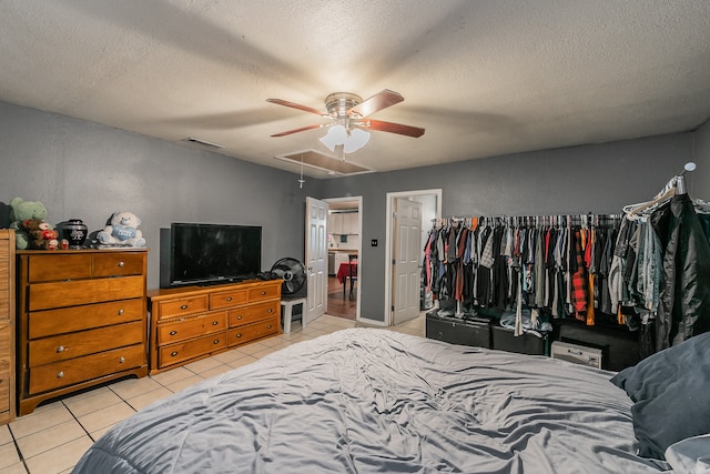 bedroom featuring light tile patterned floors, ceiling fan, a closet, and a textured ceiling