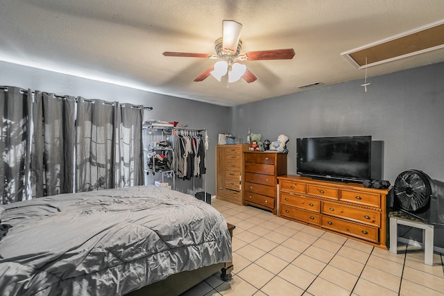 tiled bedroom with a textured ceiling, ceiling fan, and a closet