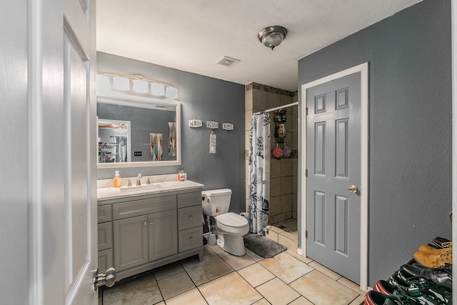 bathroom featuring tile patterned flooring, vanity, toilet, and walk in shower