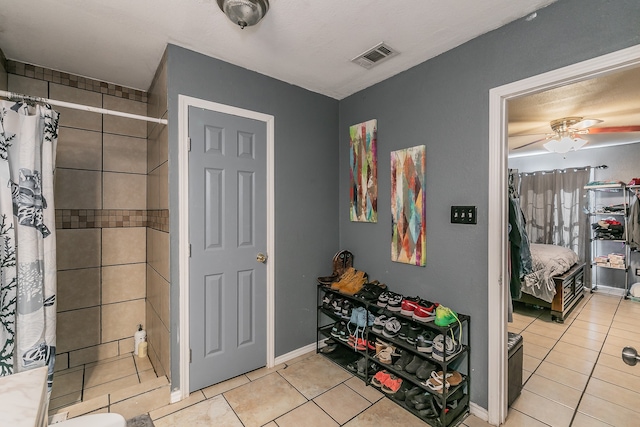 bathroom featuring walk in shower, ceiling fan, and tile patterned floors