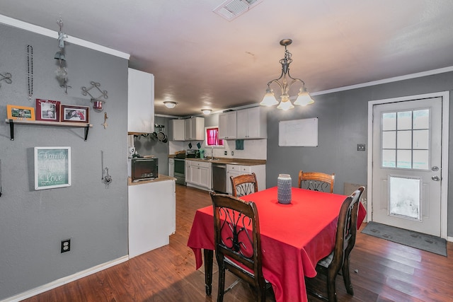 dining area with crown molding, dark hardwood / wood-style floors, sink, and a notable chandelier