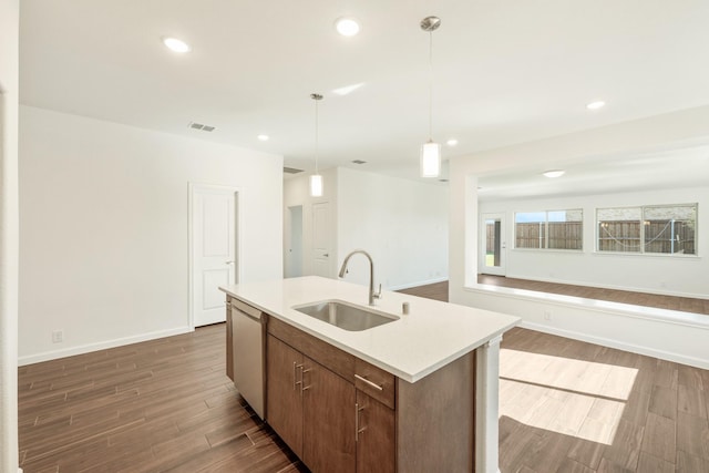 kitchen with sink, dishwasher, a kitchen island with sink, dark hardwood / wood-style floors, and decorative light fixtures