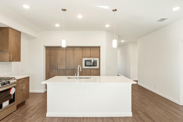 kitchen with a kitchen island with sink, sink, pendant lighting, and stainless steel gas range