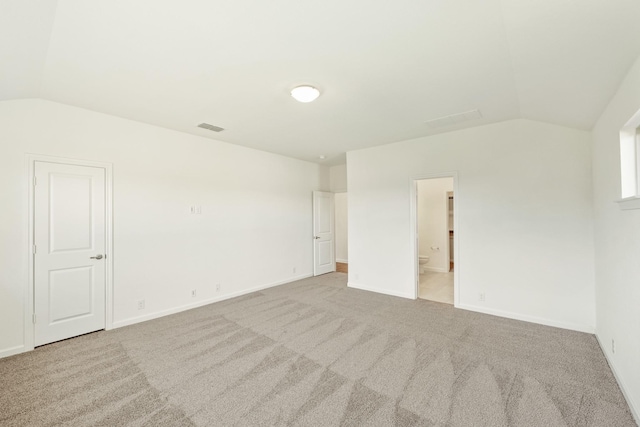 spare room featuring lofted ceiling and light colored carpet