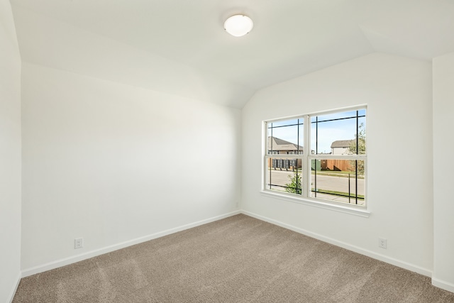 carpeted spare room featuring vaulted ceiling