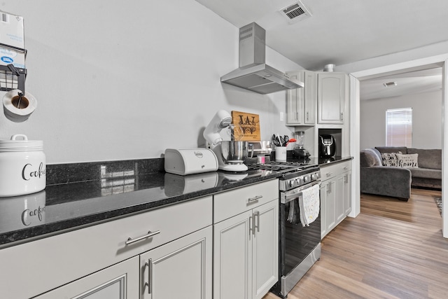 kitchen with dark stone countertops, high end stainless steel range, white cabinetry, extractor fan, and light hardwood / wood-style floors