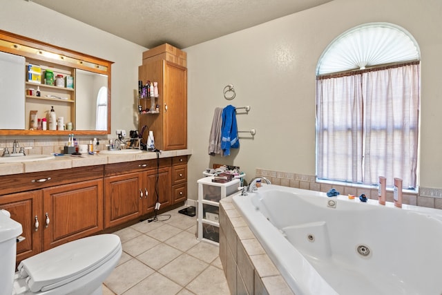 bathroom with tiled tub, toilet, tile patterned flooring, vanity, and a textured ceiling