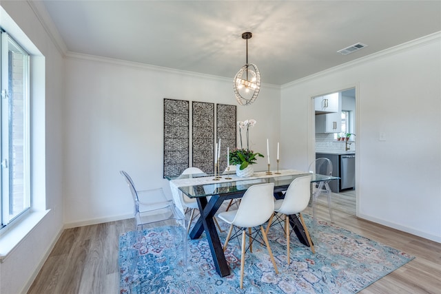 dining area with light wood-type flooring and ornamental molding