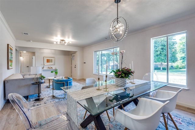 dining room with ornamental molding, light wood-type flooring, and a notable chandelier