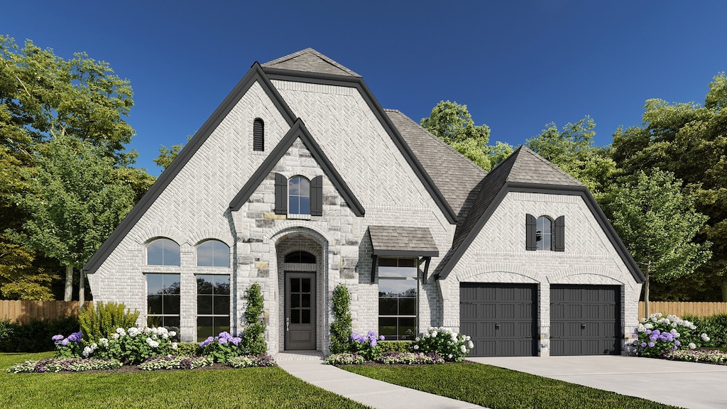 french country home featuring a front lawn and a garage