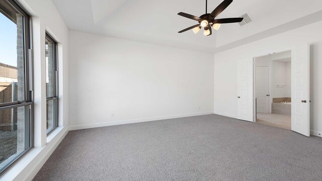 carpeted empty room featuring a raised ceiling and ceiling fan