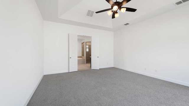 carpeted empty room with ceiling fan and a tray ceiling