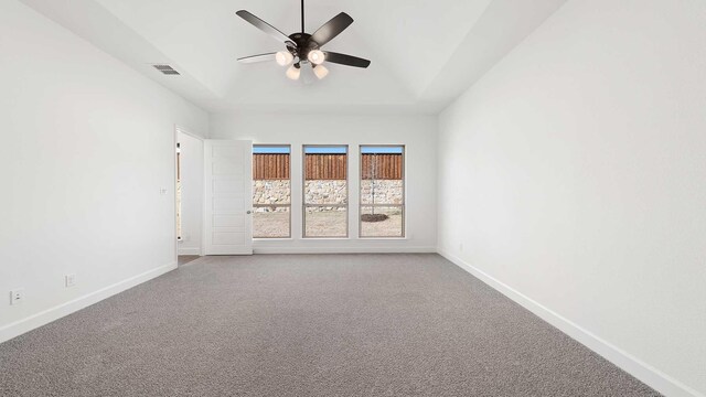 carpeted empty room with ceiling fan and a tray ceiling