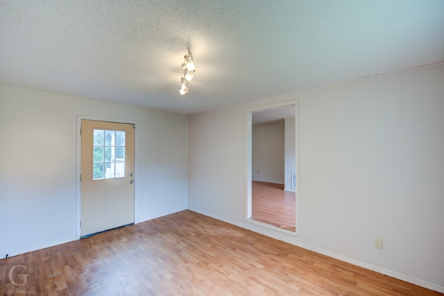 spare room featuring light wood-type flooring and a textured ceiling