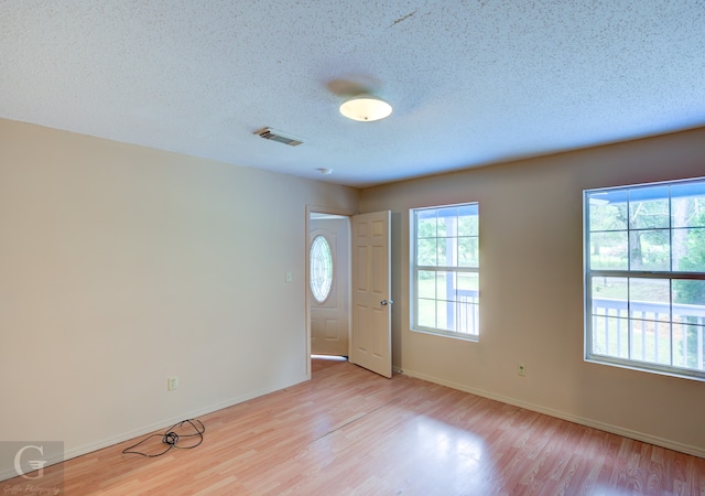 empty room featuring a textured ceiling and light hardwood / wood-style flooring