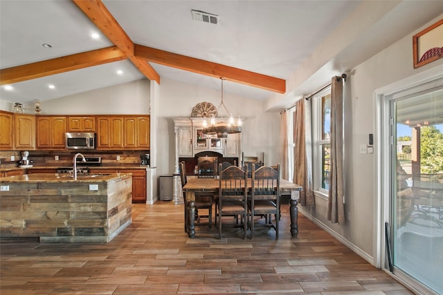 dining room with vaulted ceiling with beams, a notable chandelier, and sink