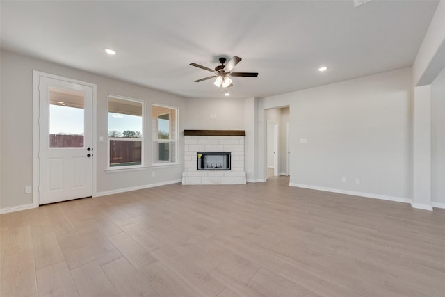 unfurnished living room featuring ceiling fan, a fireplace, and light hardwood / wood-style flooring