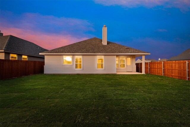 back house at dusk with a yard and a patio area