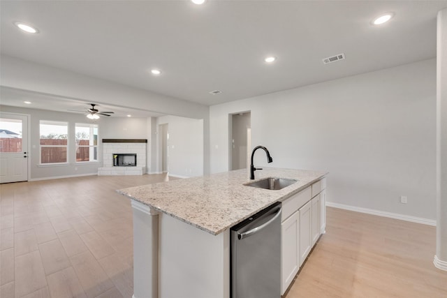 kitchen featuring a kitchen island with sink, white cabinets, sink, stainless steel dishwasher, and ceiling fan