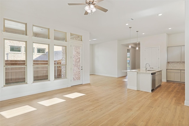 unfurnished living room with ceiling fan, light wood-type flooring, and sink