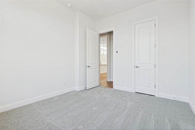 empty room featuring visible vents, carpet flooring, and baseboards
