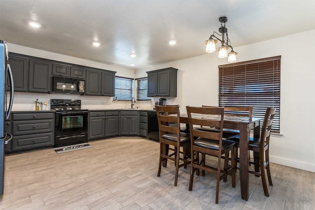 kitchen featuring a textured ceiling, light hardwood / wood-style flooring, black appliances, an inviting chandelier, and sink