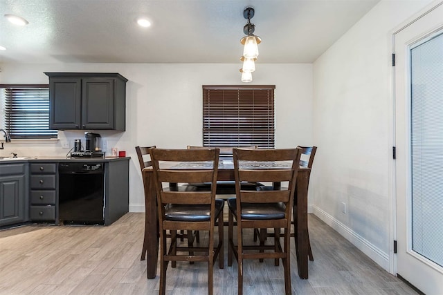 dining area with light wood-type flooring, sink, and a textured ceiling